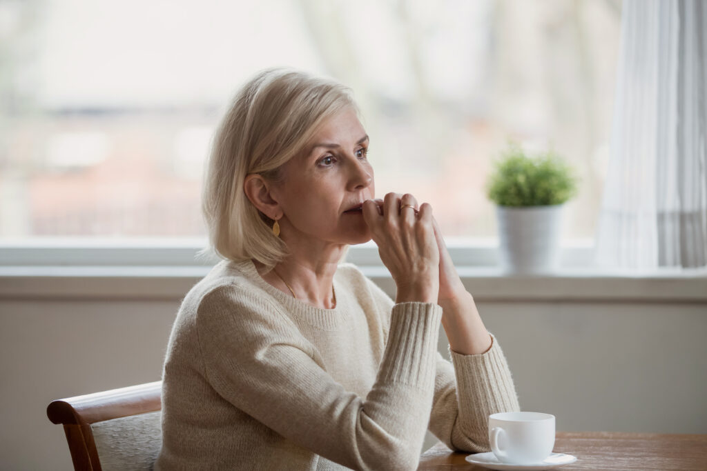 Das Bild zeigt eine nachdenkende Frau in ihrer Wohnung.